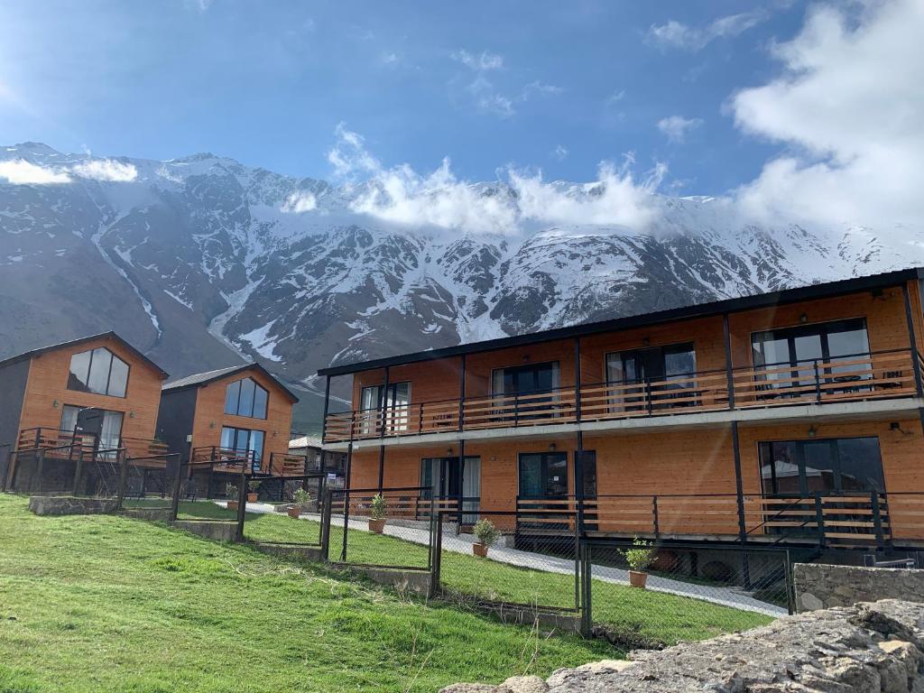 a building with a mountain in the background at Hotel & Cottages Mountain View in Kazbegi