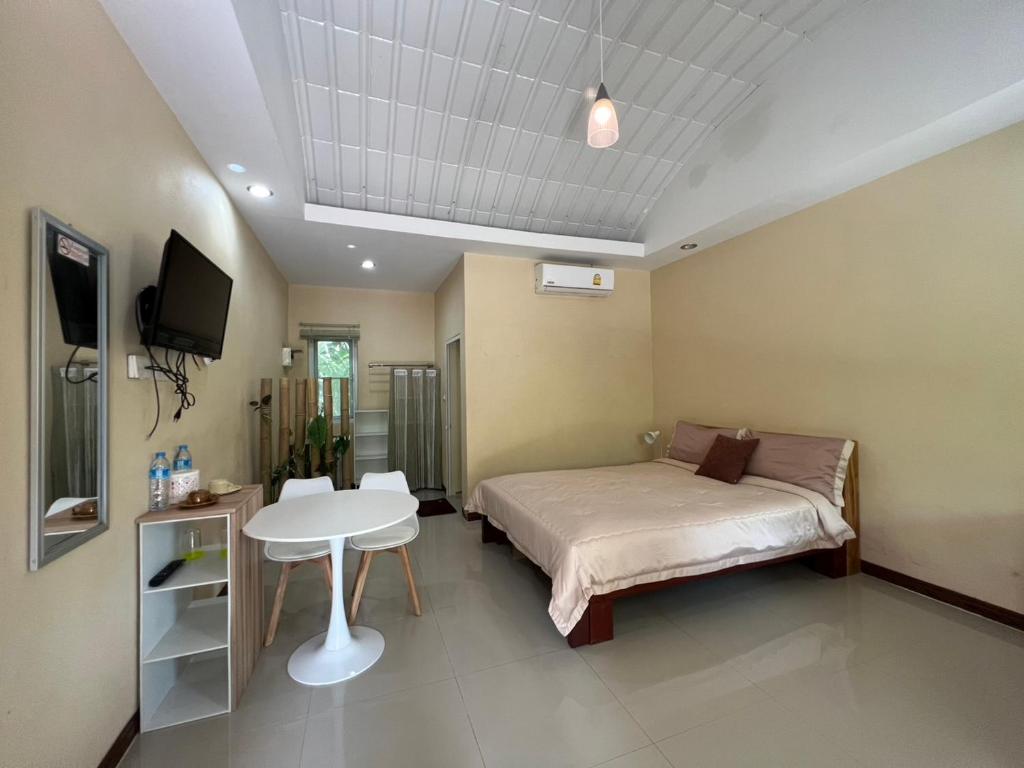 a bedroom with a bed and a table and a tv at Ariya Garden Home in Chumphon