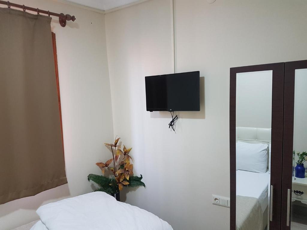um quarto com uma cama e uma televisão na parede em Agora Park Hotel em Esmirna