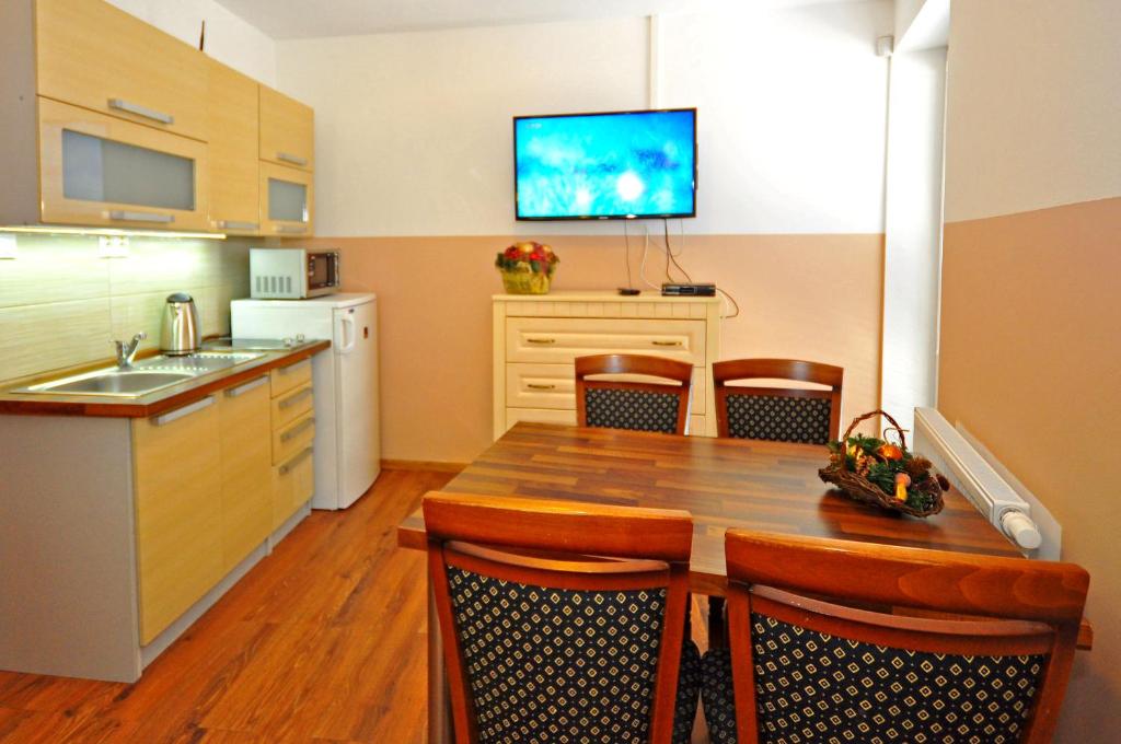 eine Küche mit einem Holztisch und einem TV an der Wand in der Unterkunft Apartment Bartek Ski Rental in Demänovská Dolina
