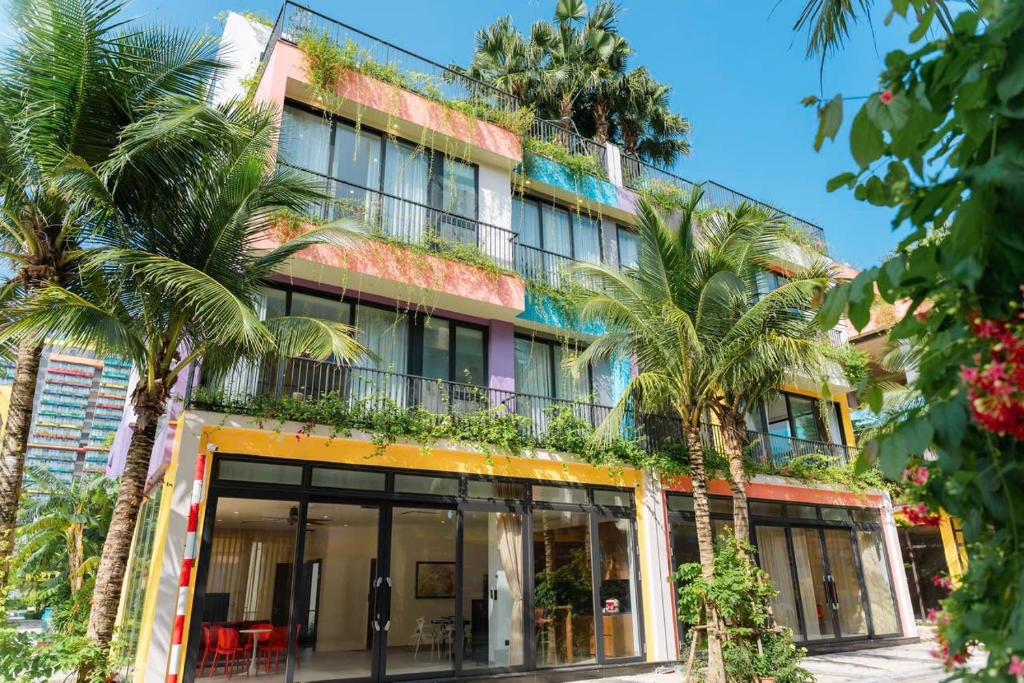a building with palm trees in front of it at Villa Flamingo Hải Tiến in Thanh Hóa
