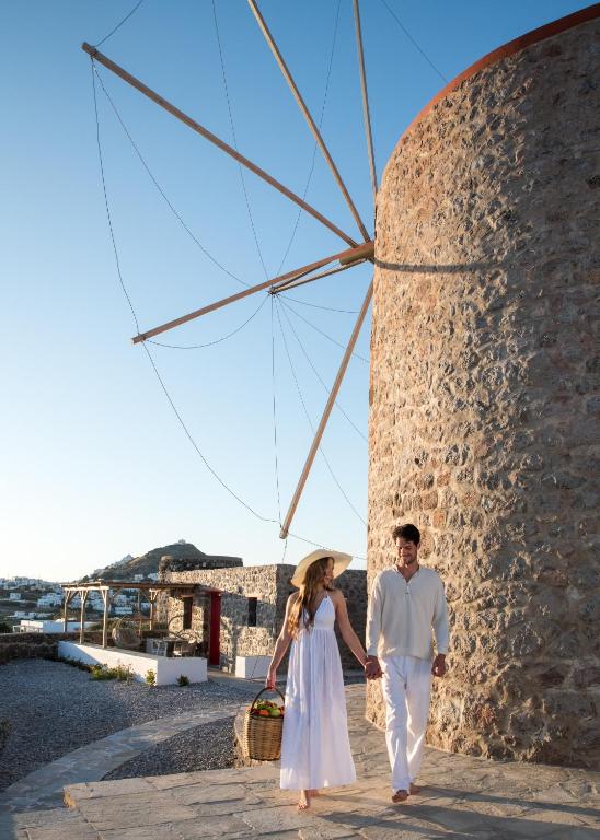 a man and a woman walking down a sidewalk next to a windmill at Marketos Traditional Windmill in Tripiti