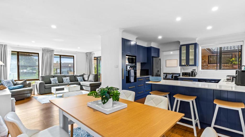 a kitchen and living room with blue cabinets and a table at Keyside Escape in Forster