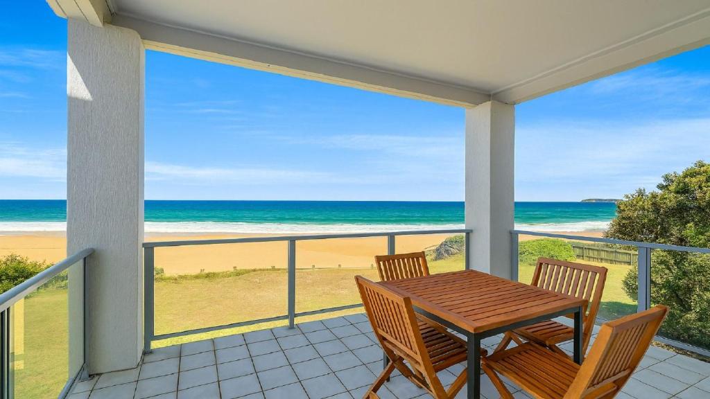 a table and chairs on a balcony with a view of the beach at Horizons in Wamberal