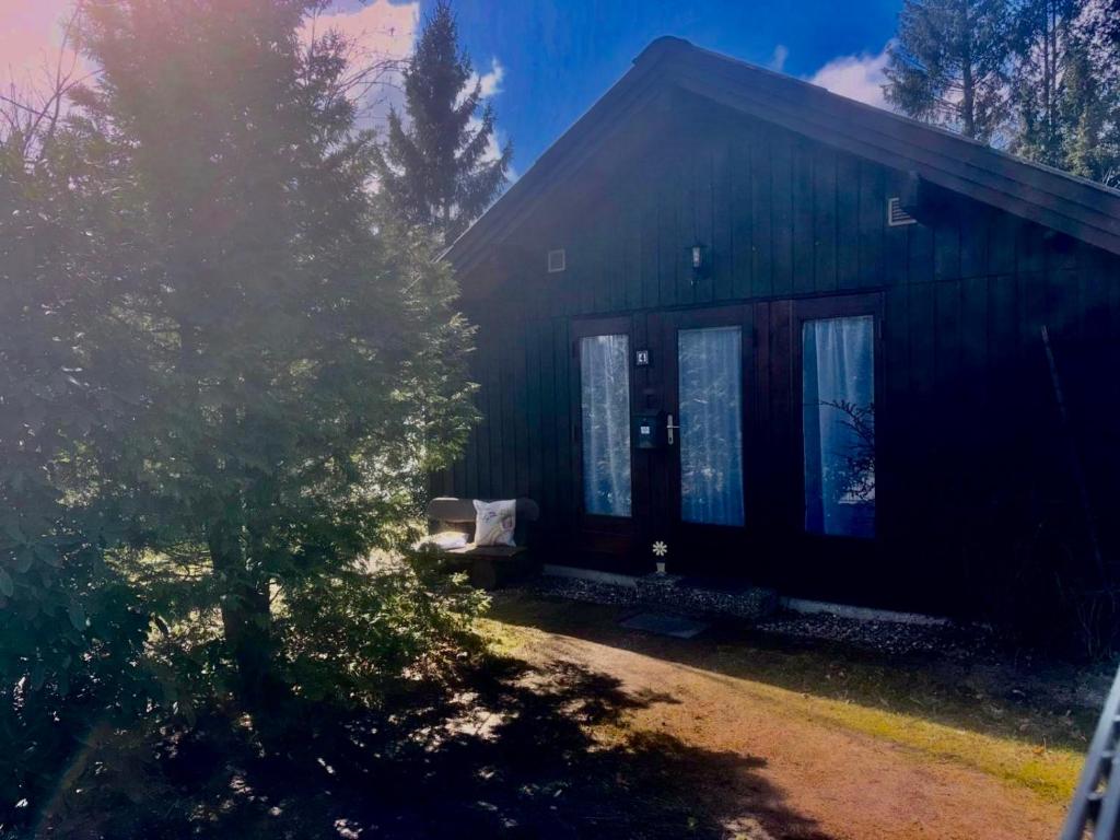a black house with a tree in front of it at Haus Sommerfeld in Meißendorf