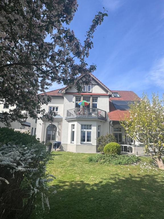 a large white house with a balcony with an umbrella at Fewo in Villa mit Seeblick in Plau am See