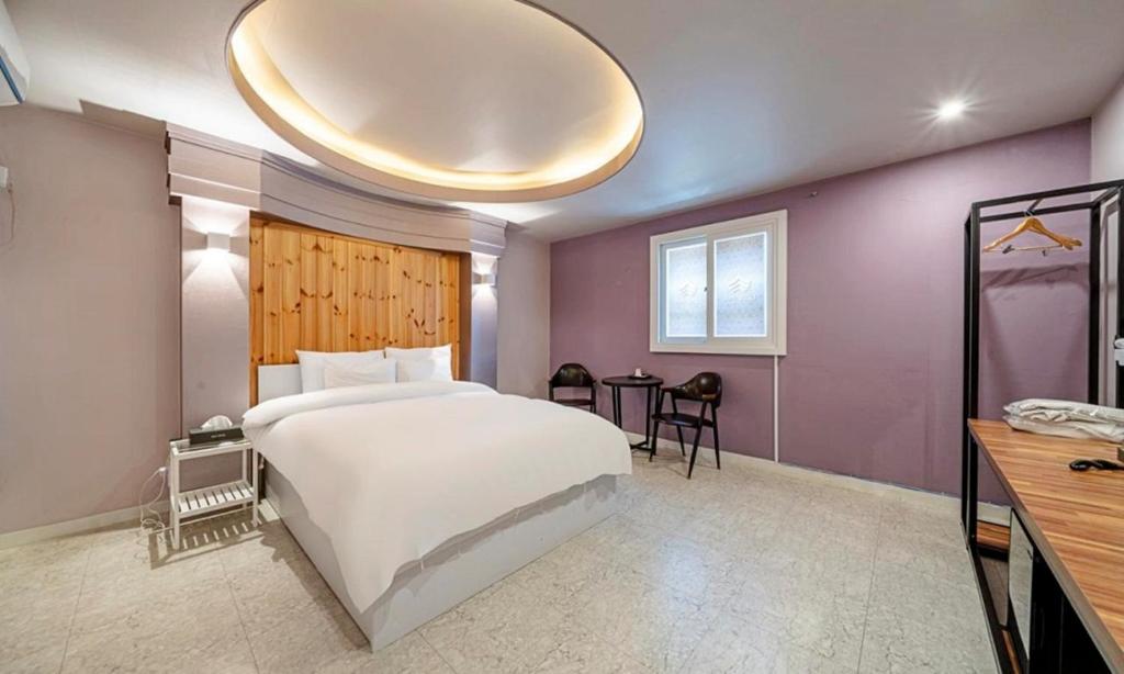 a bedroom with a large white bed and a large chandelier at 충주 호텔 발리 in Chungju