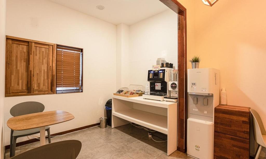 a kitchen with a refrigerator and a table with a microwave at Anyang CNC Hotel in Anyang