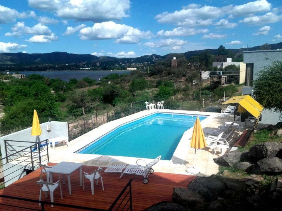 una gran piscina con sillas, mesa y mesa en Refugio Playa Perelli en Villa Carlos Paz