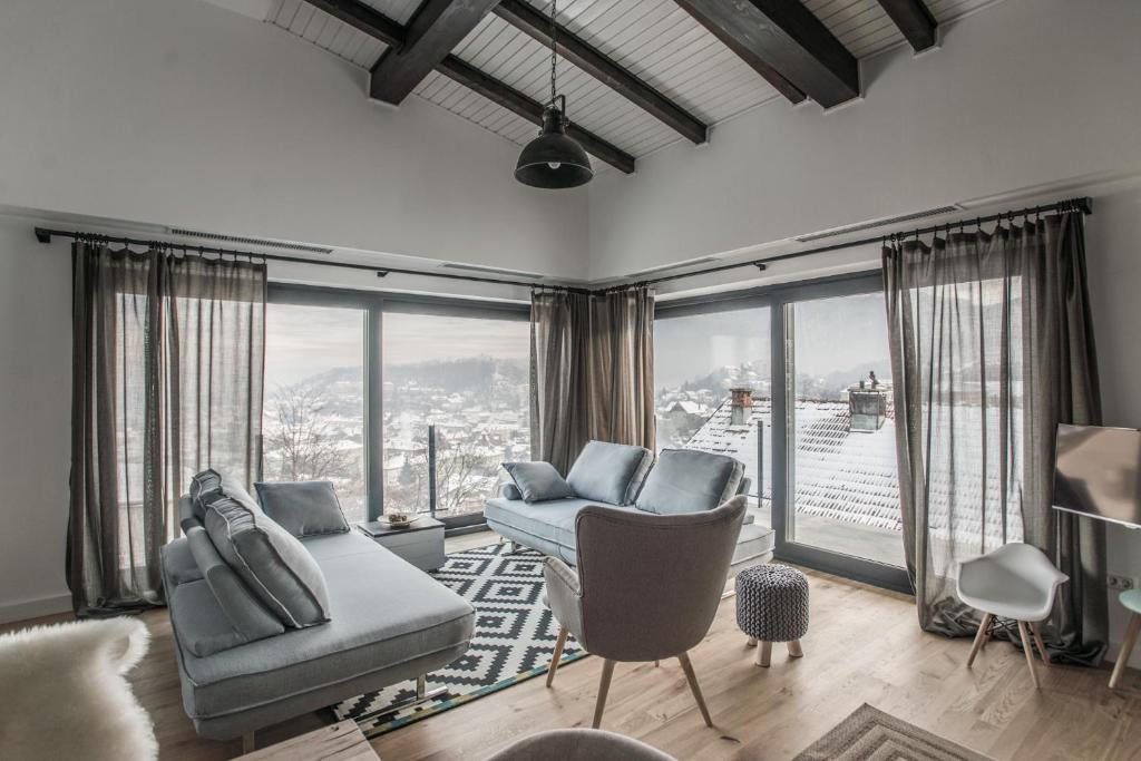 a living room with a couch and chairs and windows at The Pines Boutique Villa in Braşov