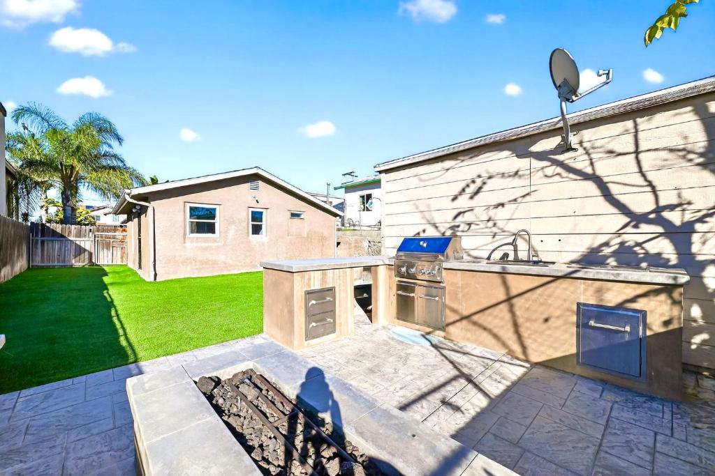a backyard with a kitchen and a yard with a house at San Diego 3BR & 3BA Comfortable Home, Outdoor Kitchen, Firepit & BBQ, 10 to 15min from SeaWorld & Zoo in San Diego