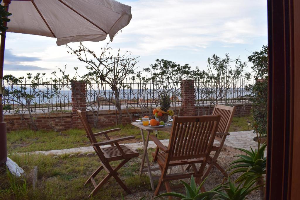 Agios OnoufriosにあるMichalis Apartmentのパティオ(テーブル、椅子2脚、パラソル付)