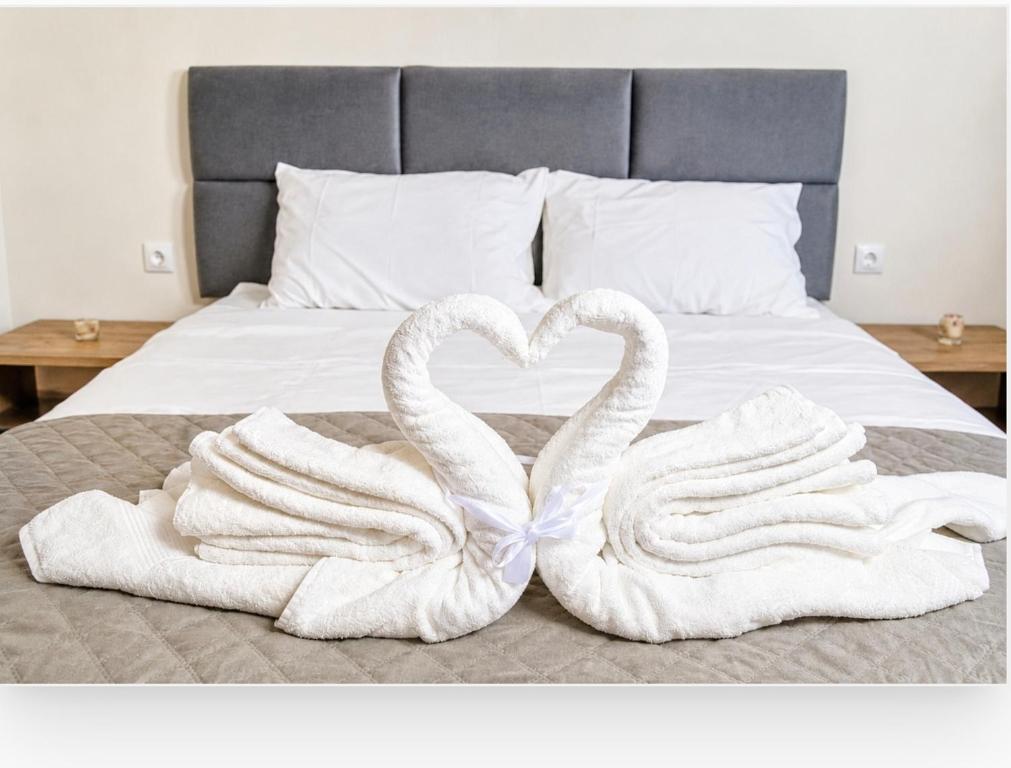 two swans towels are forming a heart on a bed at Thaleia apartment in Igoumenitsa