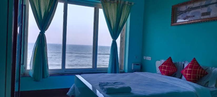 a bedroom with a bed with a view of the ocean at Sapphire Inn in Chennai