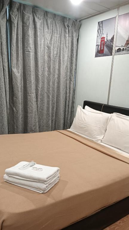 a bed with white towels on top of it at SC Lodging Sinsuran Complex in Kota Kinabalu