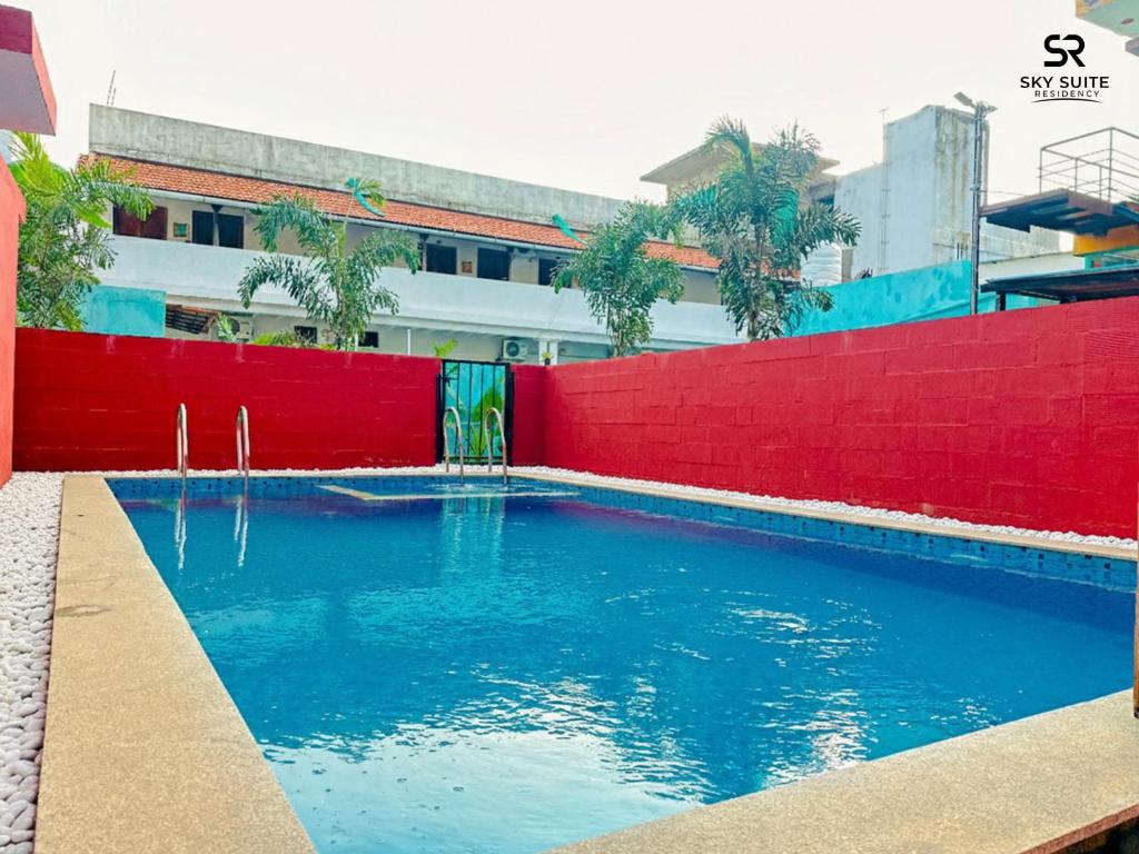 a swimming pool in front of a red fence at sky suite residency in Auroville