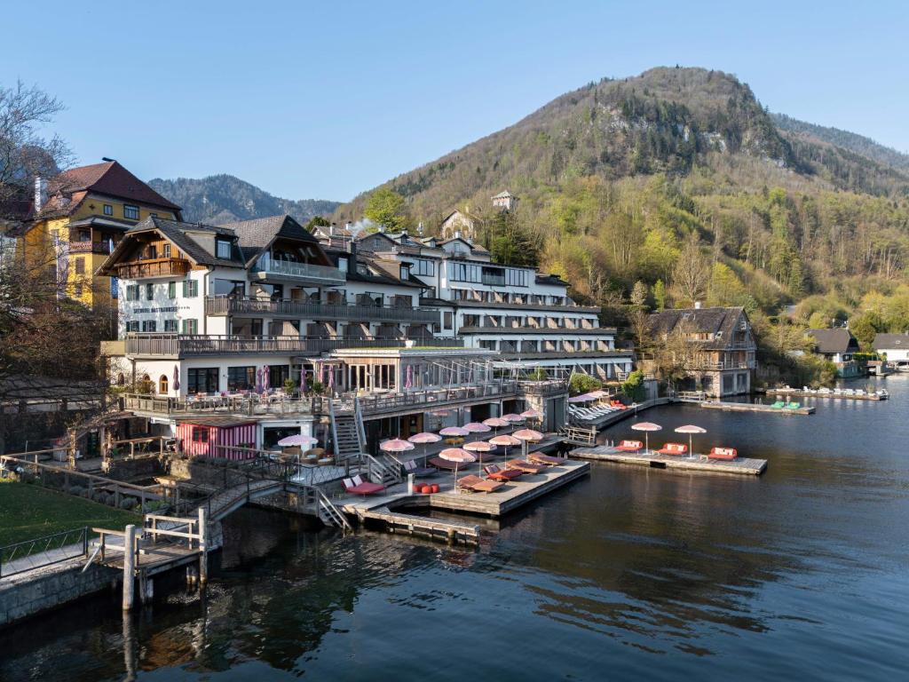 a group of buildings on the water next to a river at Das Traunsee - Das Hotel zum See 4 Stern Superior in Traunkirchen