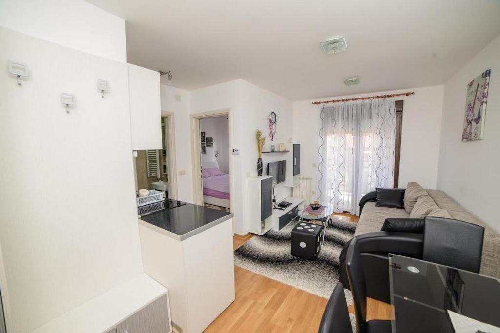 a white living room with a couch and a kitchen at Apartman Sinisa in Zlatibor