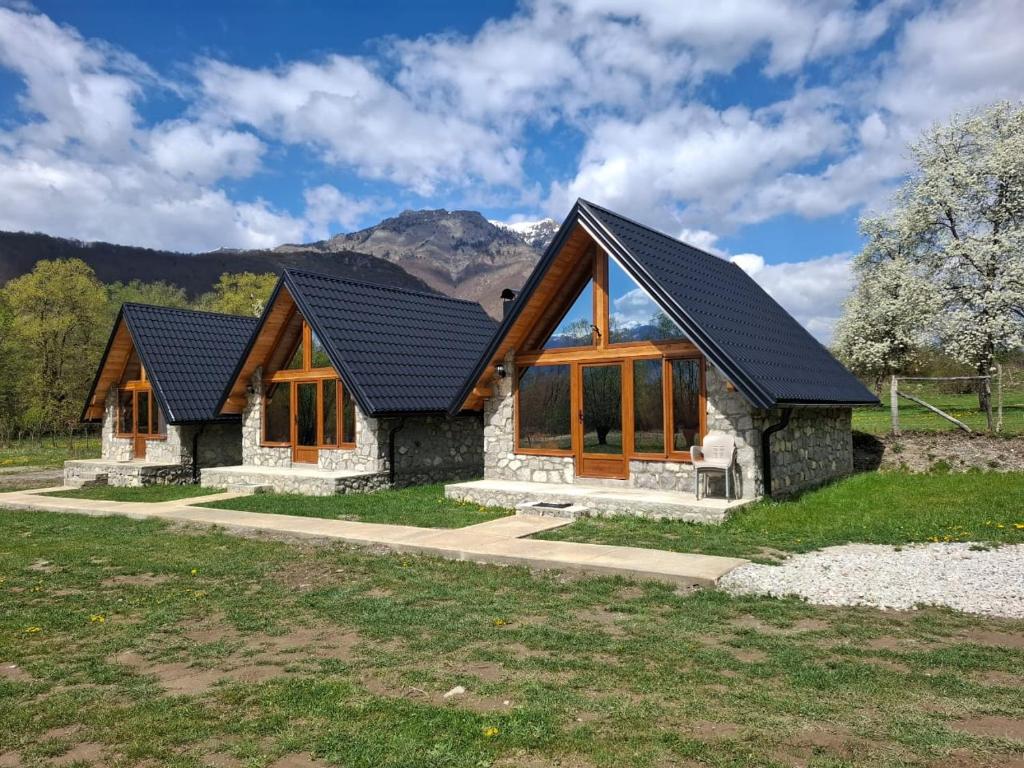 a log home with a black roof and windows at Kukaj Apartments in Gusinje