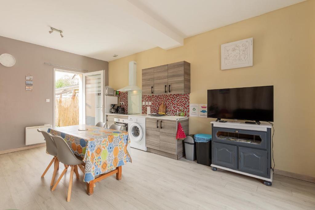 a kitchen with a dining room table and a tv at Gîte Escale En Baie De Somme in Saint-Blimont