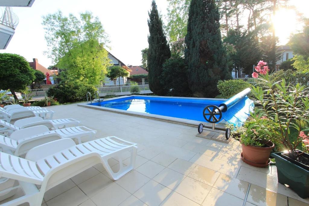 a group of white lounge chairs next to a swimming pool at Aquasol Apartman in Siófok