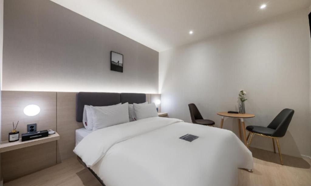 a bedroom with a white bed and a table and chairs at Pohang Mansion 6 Hotel in Pohang