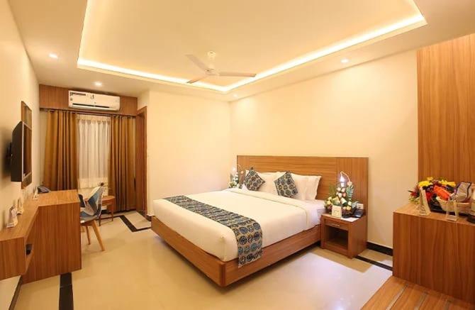 a hotel room with a bed and a television at Heyday INN in Pathanāmthitta