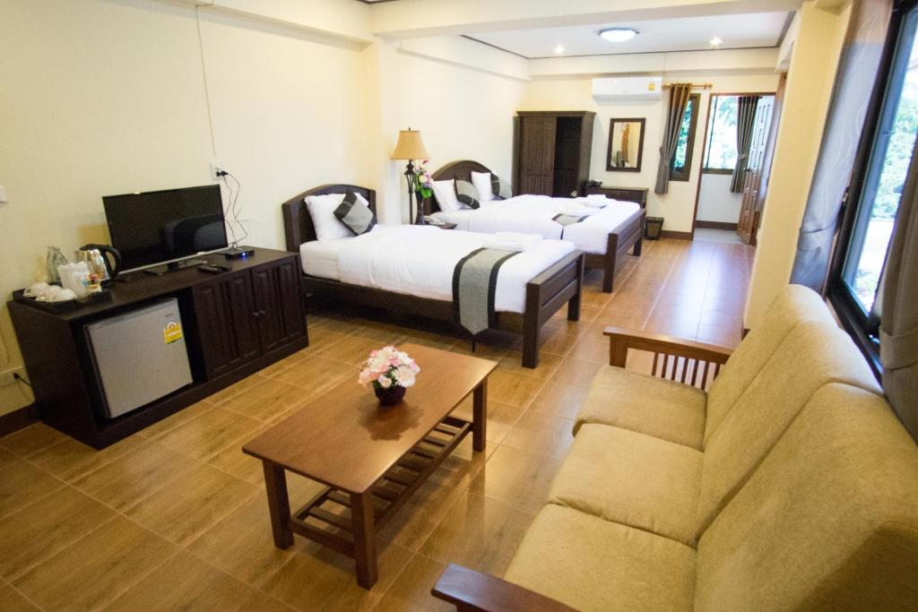 une chambre d'hôtel avec deux lits et un canapé dans l'établissement NanBaanKhun Hotel, à Nan