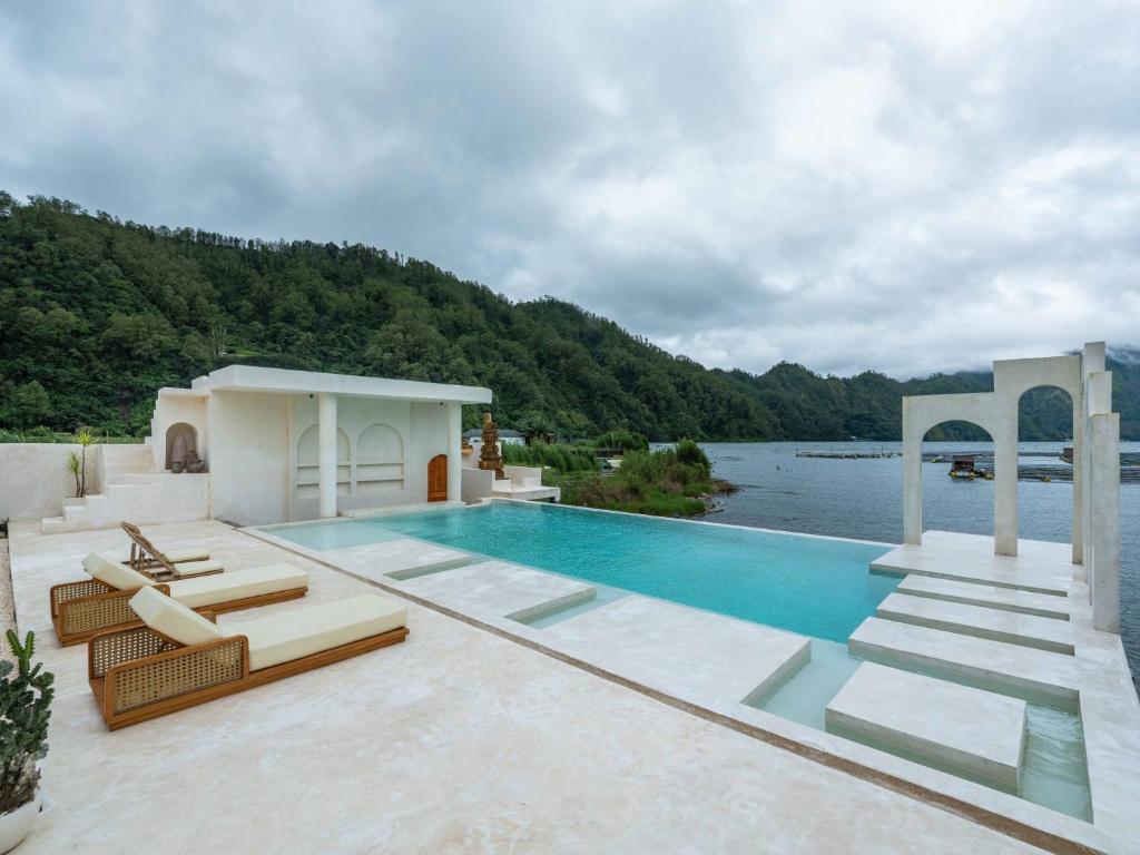 a swimming pool on a house with a lake at Holista Bali in Kubupenlokan