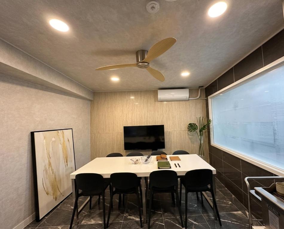 a dining room with a table and a ceiling fan at Billy Hostel in Busan