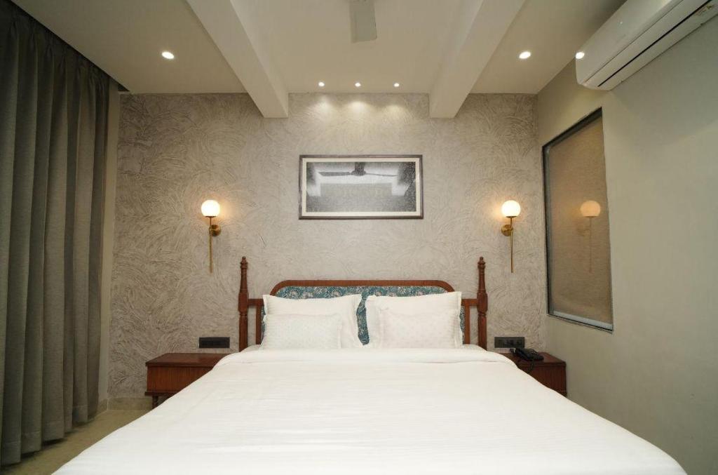 a bedroom with a large bed with white sheets at Hotel manju श्री in Pachmarhī