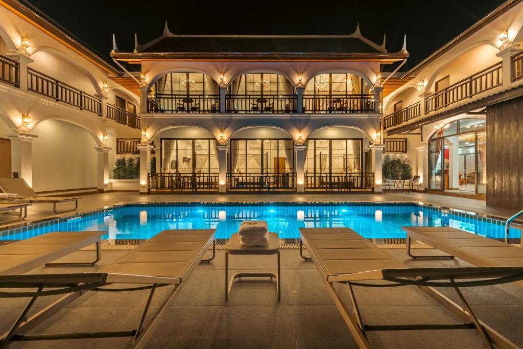 a swimming pool with tables and chairs in a building at The Jam Central in Luang Prabang