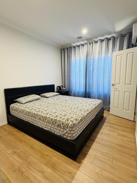 a bedroom with a bed and a window with blue curtains at Feels Like Home in Wyndham Vale