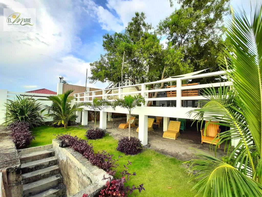 a white building with tables and chairs in a yard at Villa El Marie in Bacnotan
