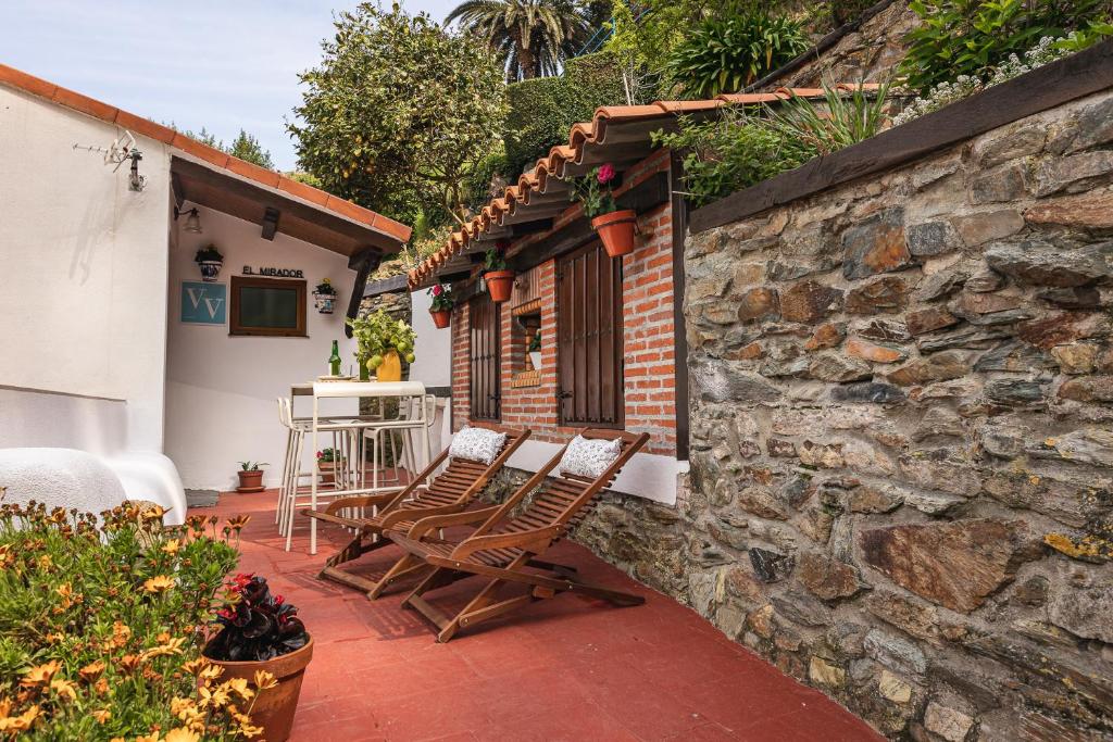 a patio with two chairs and a stone wall at El Mirador in Cudillero