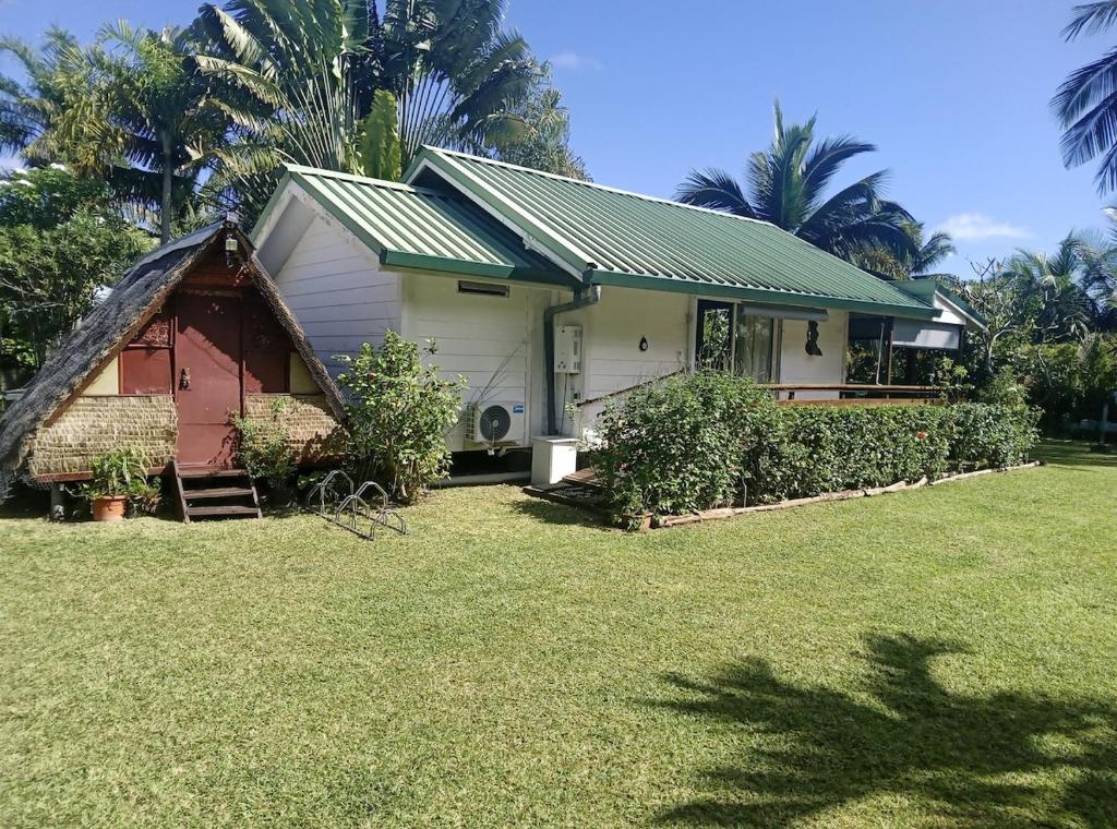 a house with a green roof and a yard at Chez Teivama in Haapiti