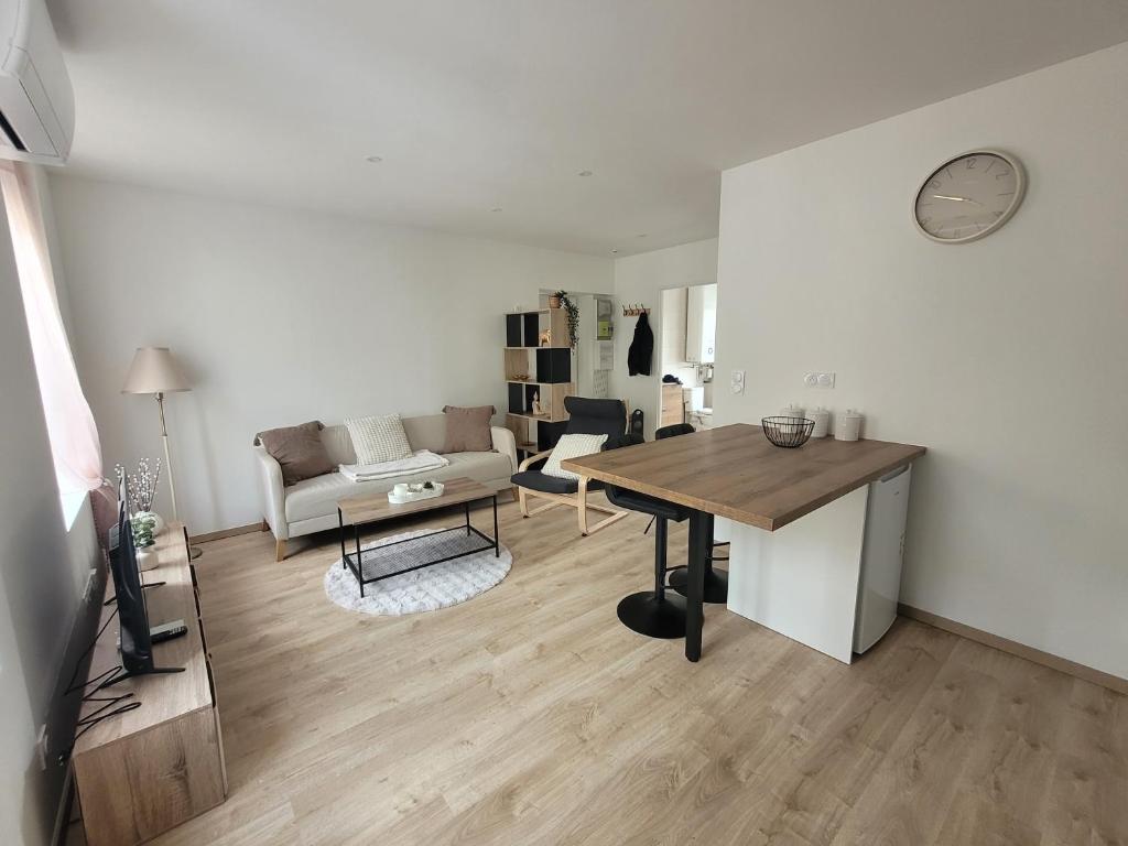 a living room with a table and a couch at Appartement cosy in Commentry