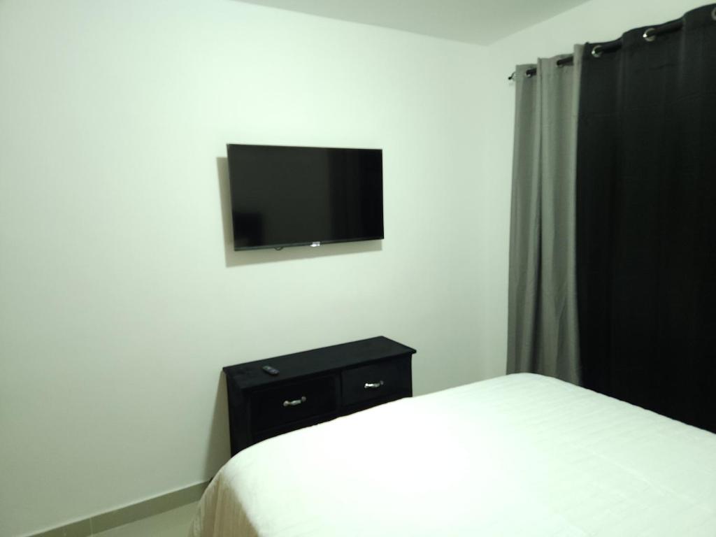 a bedroom with a bed and a tv on a wall at Charming home in Cancino