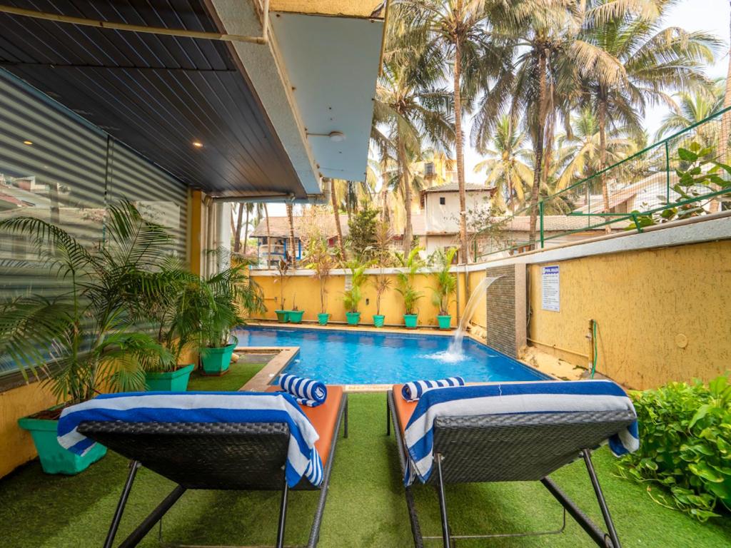 a balcony with two chairs and a swimming pool at Trevon Hotels & Resorts Candolim Goa in Candolim