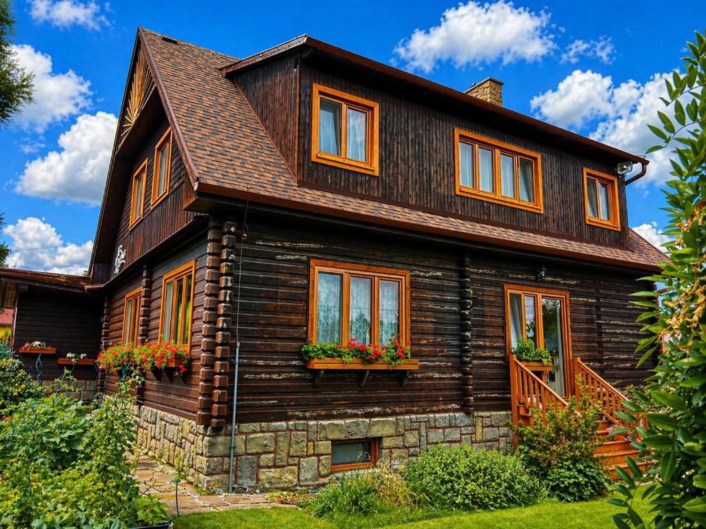 a wooden house with flowers in the windows at Penzion V peřině in Trojanovice
