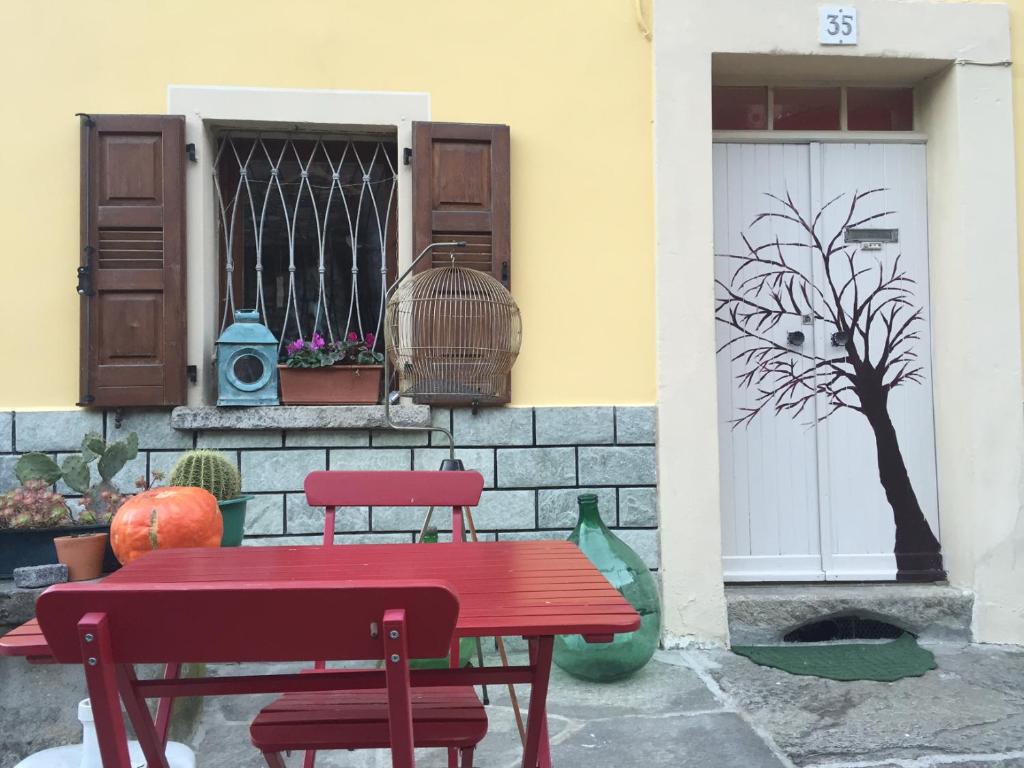 uma mesa vermelha e cadeiras em frente a um edifício em B&B Valle Spluga Il Pertugio em Chiavenna
