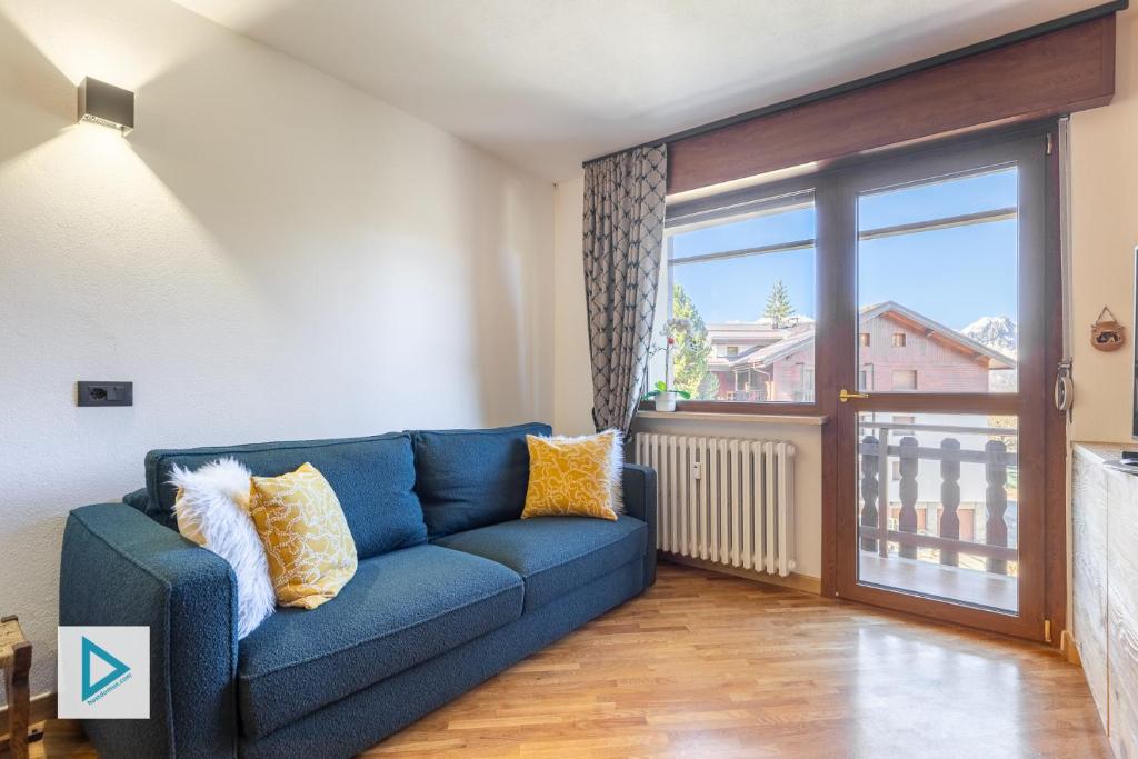 a blue couch in a living room with a large window at Hostdomus - Clotes Dream Suite in Sauze d'Oulx
