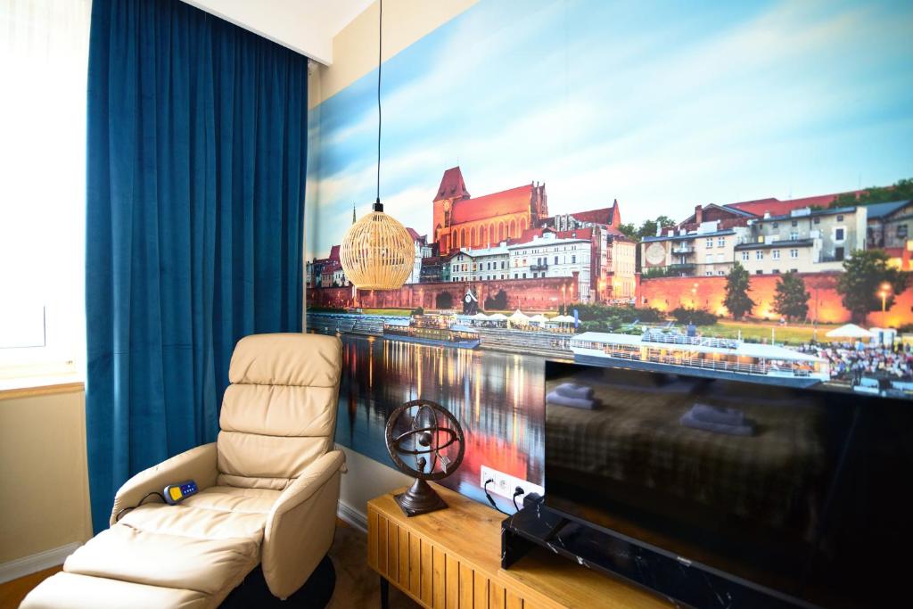 a living room with a large tv and a chair at City Stay Kaszownik AC Progres in Toruń