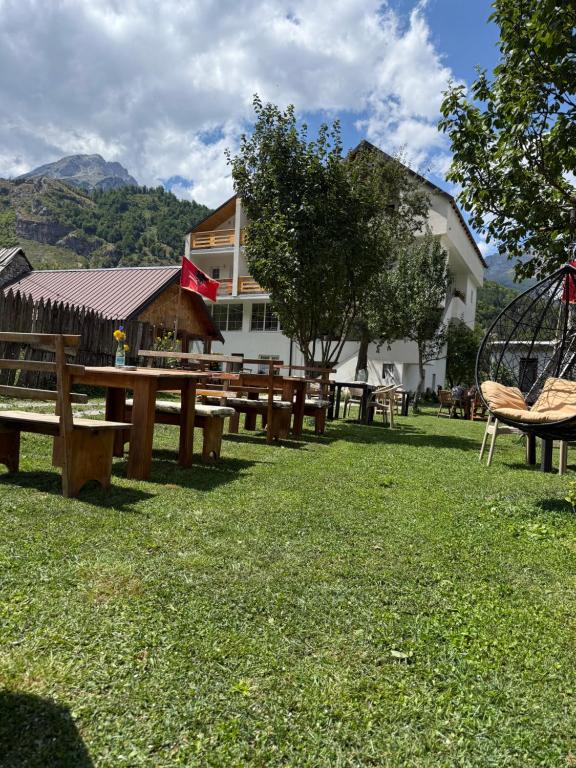 a group of picnic tables in a grass field at Guesthouse Skender Selimaj in Valbonë