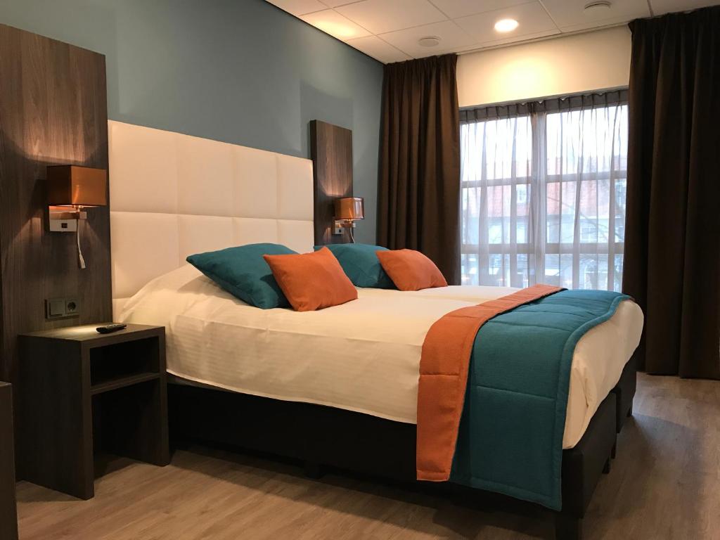 una camera da letto con un grande letto con cuscini arancioni e blu di Rivers Hotel a Sluis