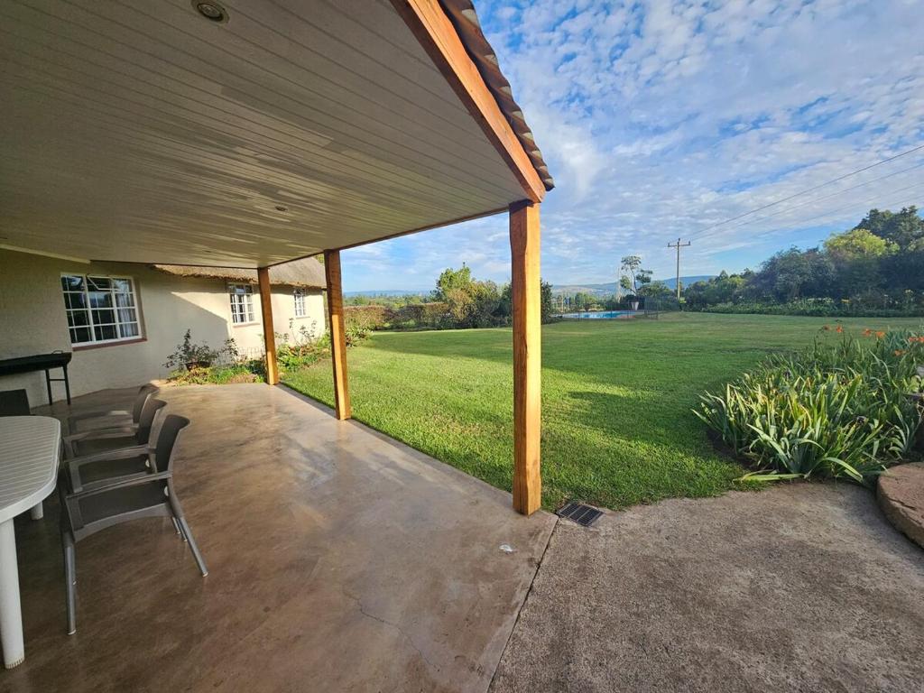 a covered patio with a table and chairs and a field at Pearse Farm Stay in Howick