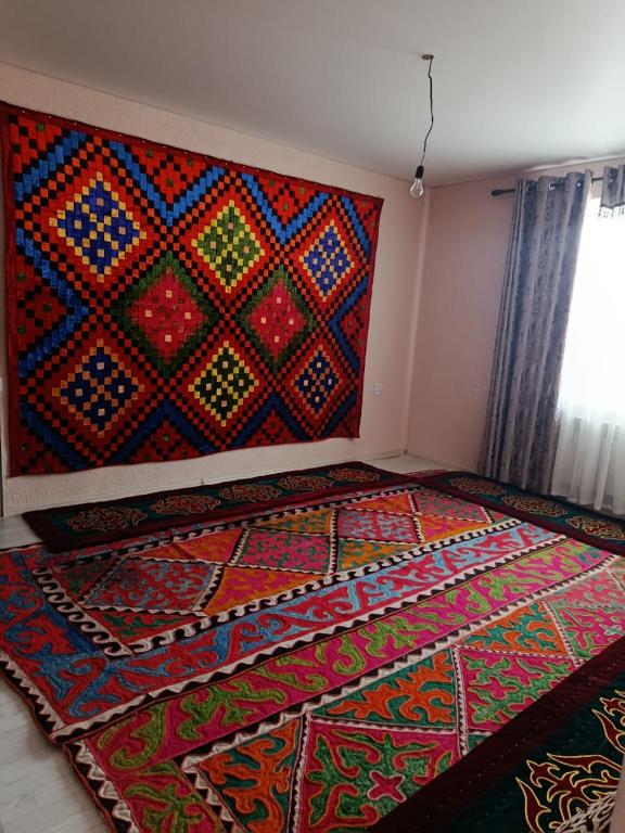 a room with a colorful rug on the wall at SunLake House in Balykchy