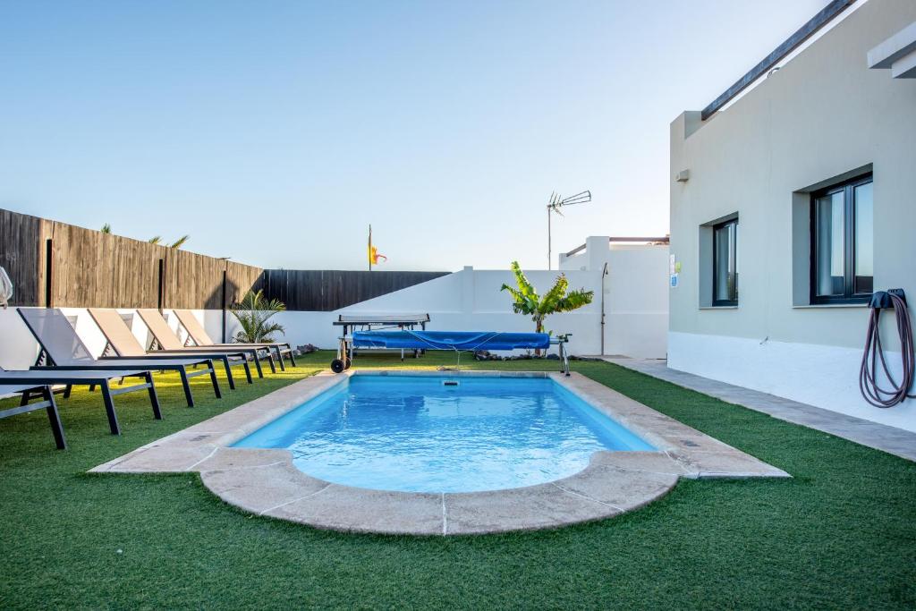 a backyard with a swimming pool and grass at Ereza Villas Alicia in Caleta De Fuste