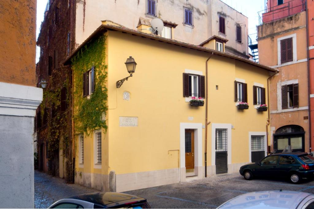 un bâtiment jaune avec une voiture garée dans une rue dans l'établissement La Gensola In Trastevere, à Rome