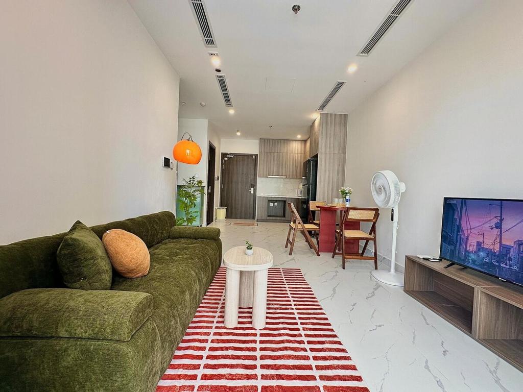 a living room with a green couch and a tv at 1BR Olive & Rouge House in Long Bình